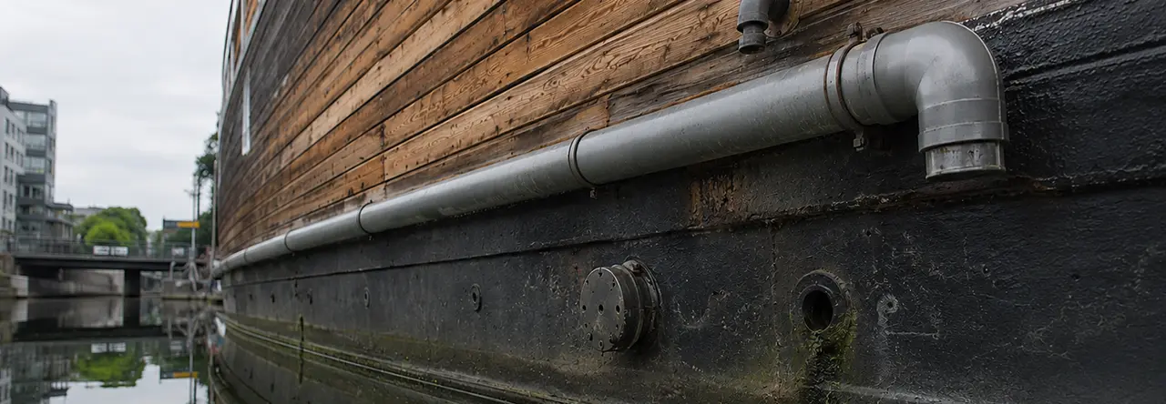 Hausboot mit Wasserauslässen in einem Kanal